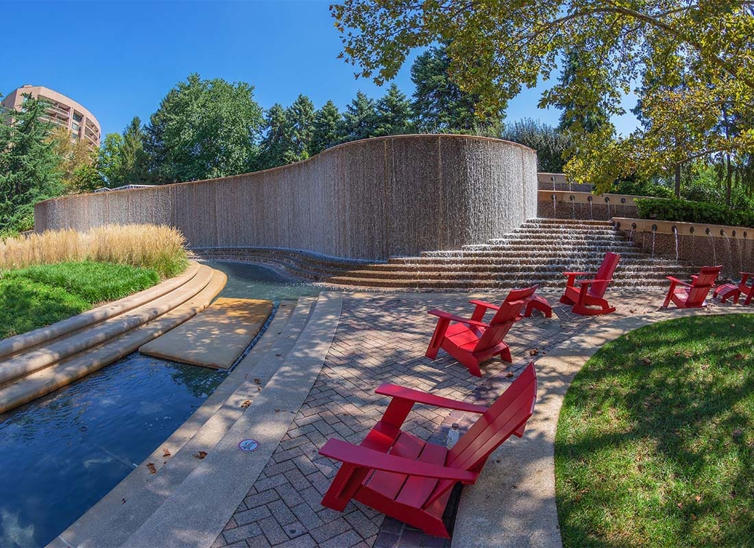 Business Partners - View of Red Wooden Chairs in a Modern Park with a Fountain and Curved Stone Walls in Crystal City Virginia