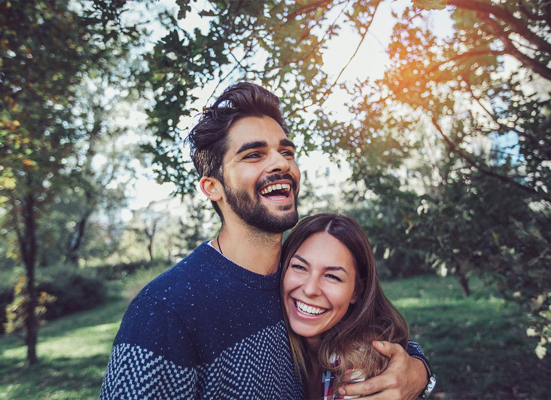 Life Insurance - Portrait of a Cheerful Young Couple Spending Time Together in a Park with Green Trees on a Sunny Day