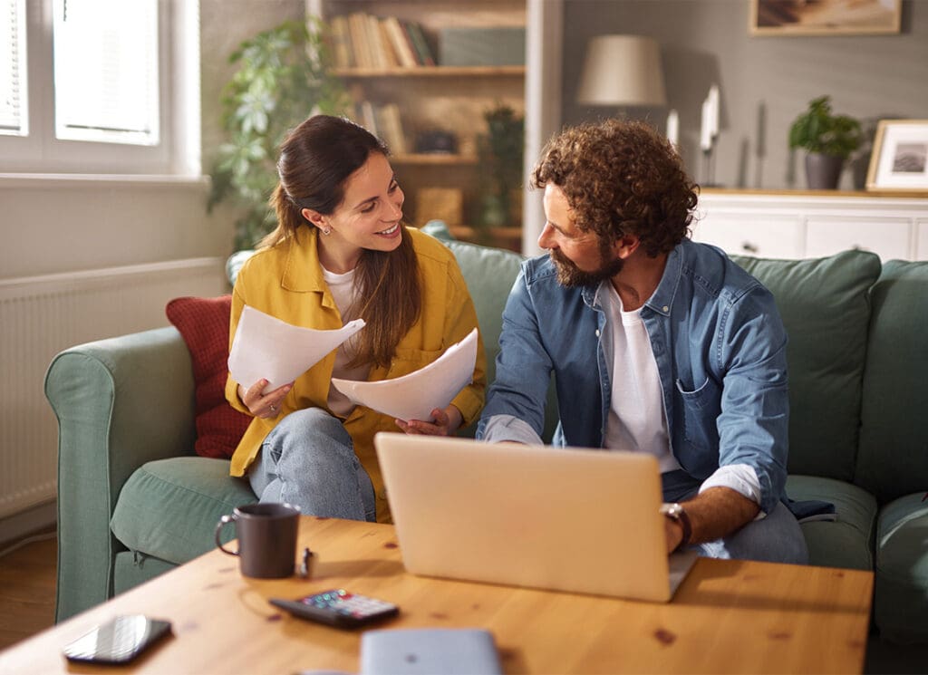 Most Affordable Virginia Life Insurance - Couple Reviewing Documents With Laptop in Living Room