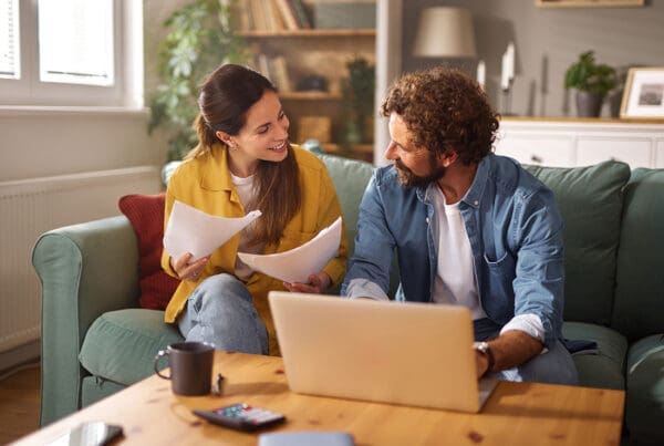 Most Affordable Virginia Life Insurance - Couple Reviewing Documents With Laptop in Living Room